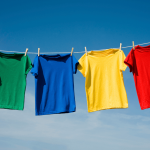Four brightly colored tee shirts hanging on clothesline